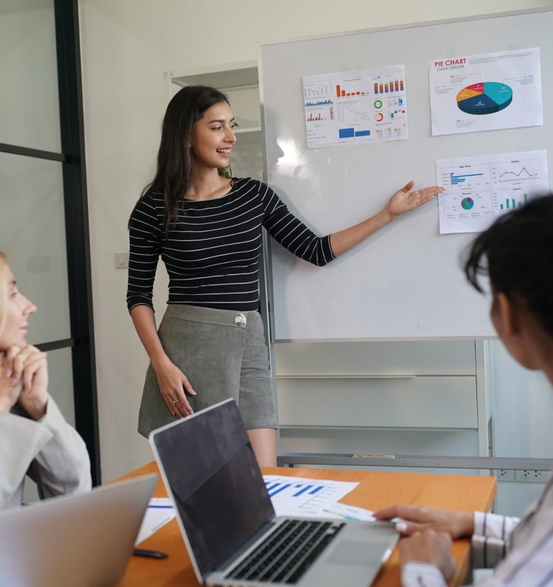 Businesswoman Pointing At Charts On whiteboard During Corporate Meeting Indoor